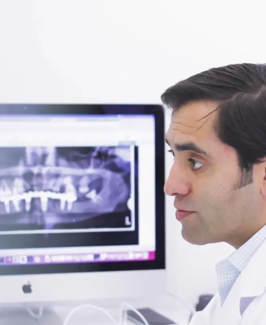 Odontólogo revisando una radiografía panorámica en la pantalla del computador