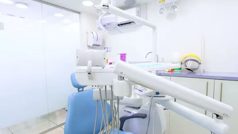Box de atención con el sillón dental, la lámpara y la bandeja de instrumental preparada