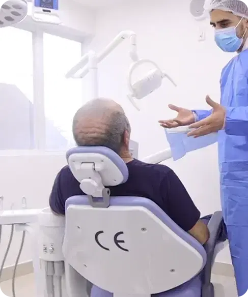 Profesional de la clínica explicando el procedimiento a un paciente en el sillón dental