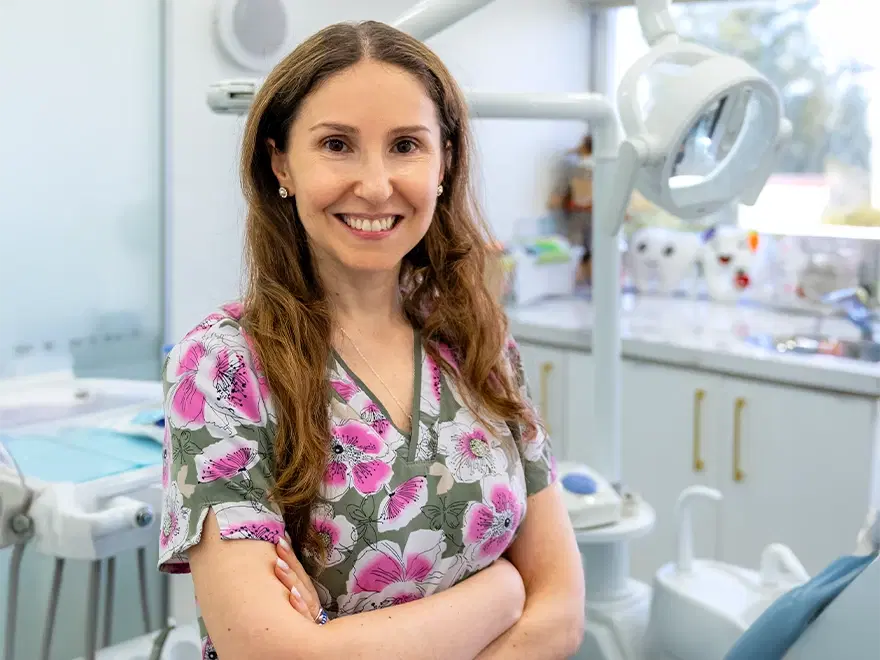 Dra. Javiera Poblete, de Dentistas por Chile, sonriendo con los brazos cruzados en el box de odontopediatría