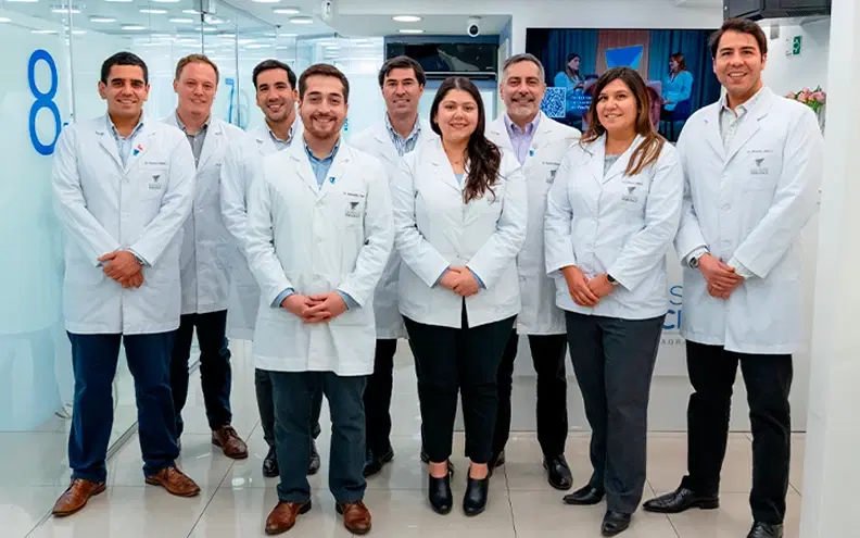Equipo de odontólogos de Dentistas por Chile, con delantal blanco, de pie en la clínica