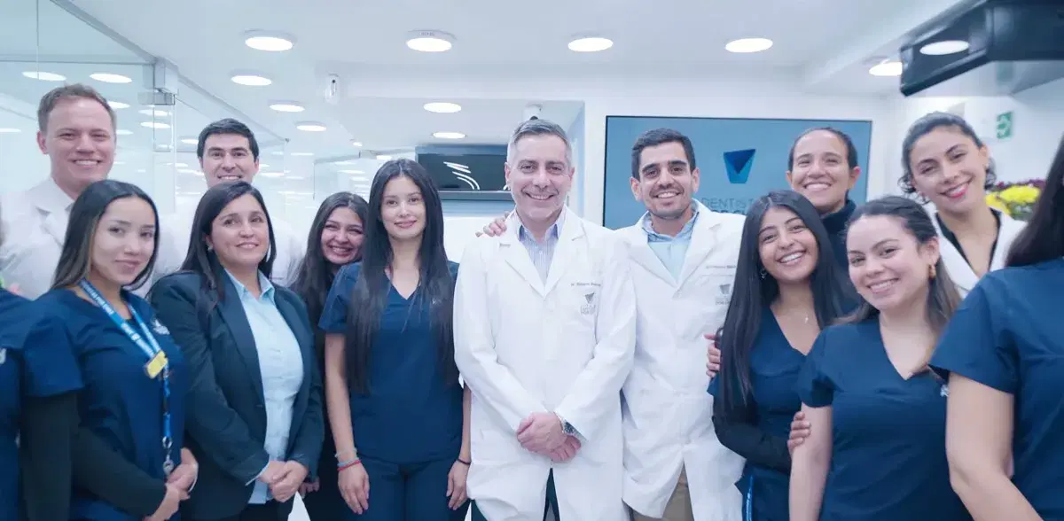 Equipo clínico y administrativo de la clínica reunido en el pasillo, con delantales blancos y uniformes azules