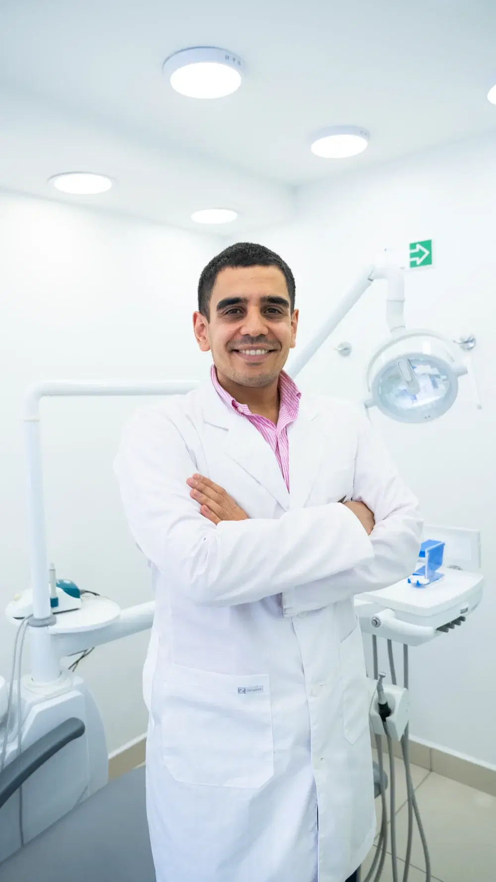 Dr. Francisco Nahum, dentista de Dentistas por Chile, sonriendo con los brazos cruzados en el box de atención