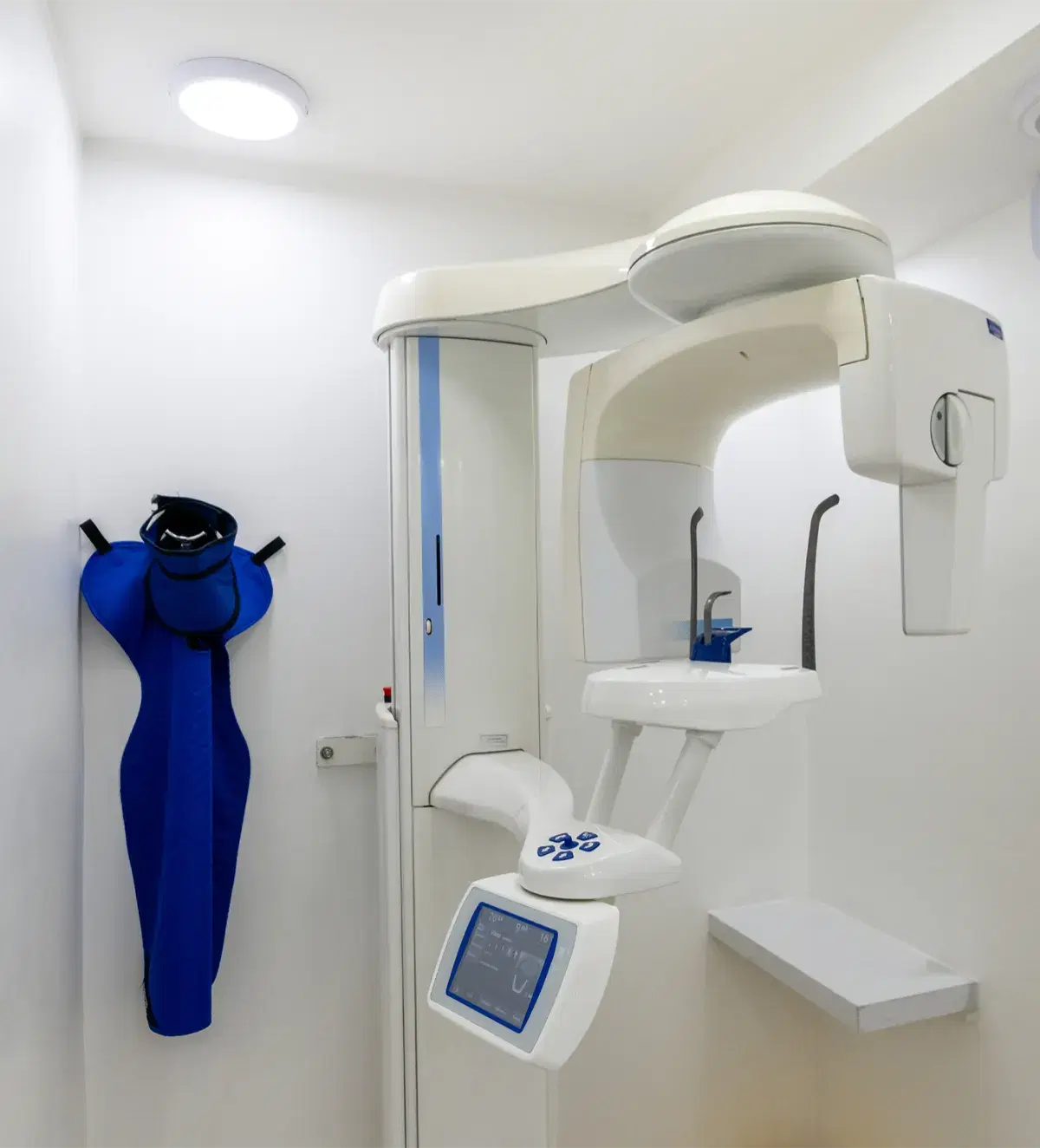 Equipo de radiografía panorámica y escáner 3D del centro radiológico, con el delantal plomado colgado al lado