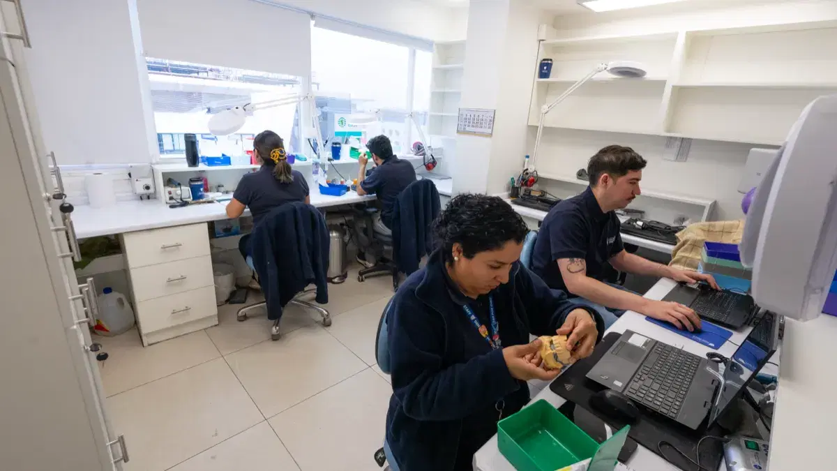Técnicos del laboratorio dental de la clínica trabajando en sus puestos con modelos y computadores