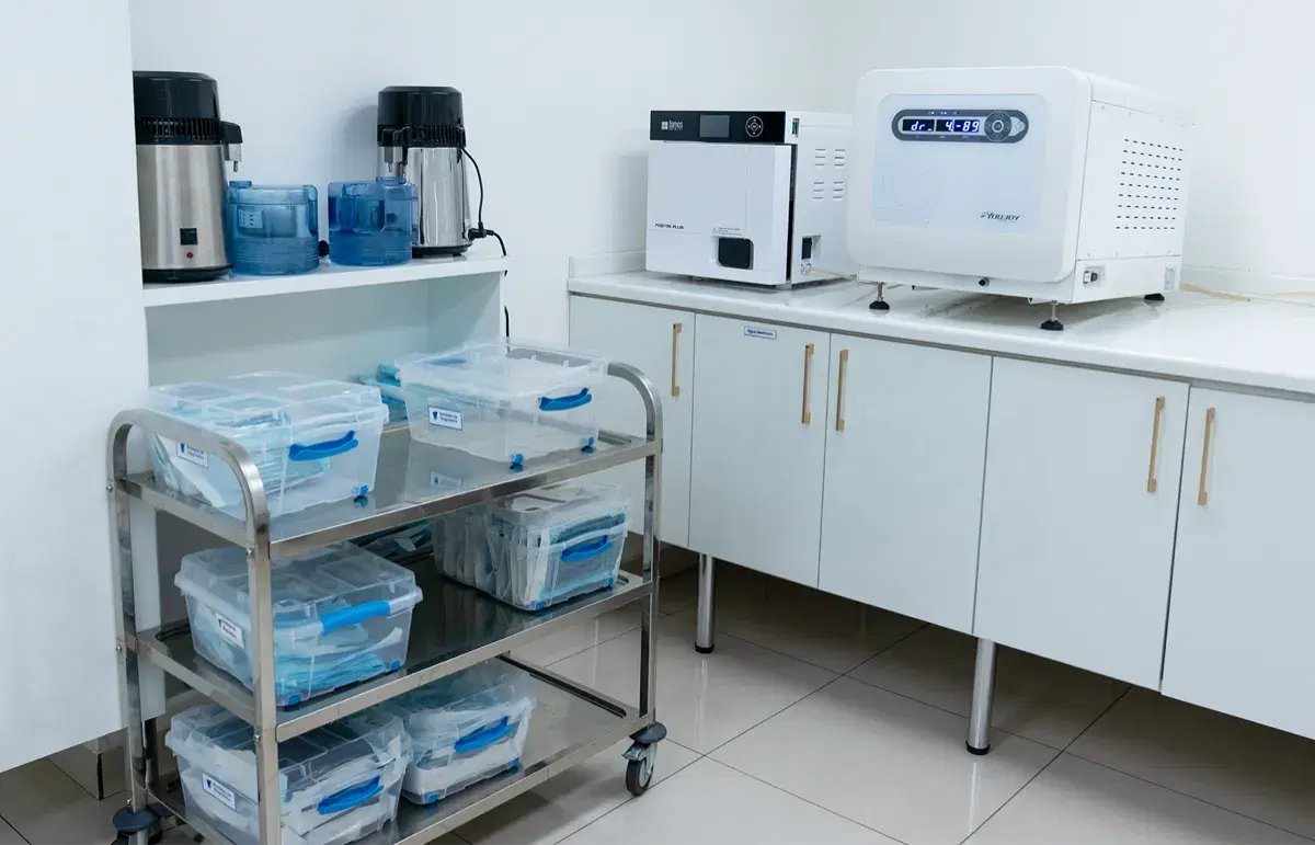 Unidad de esterilización con autoclaves sobre el mesón y carro con cajas de instrumental